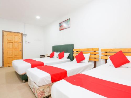 a room with four beds with red and white sheets at Citra Kadok Hotel & Banquet Hall in Kota Bharu