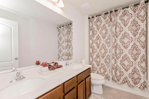 a bathroom with a sink and a toilet and a shower curtain at Spacious 4 Bed Home near Orlando Gated Pool Access in Sanford