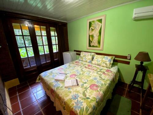 a bedroom with a bed with a floral comforter at Pousada Donna Rose in Penedo