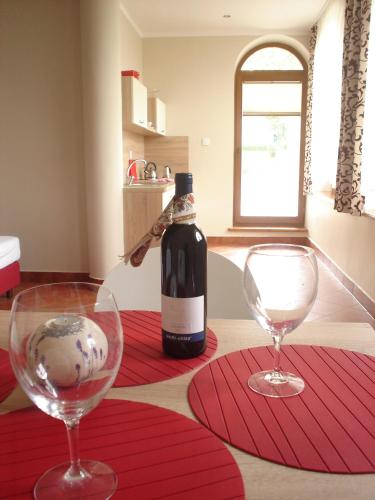 a bottle of wine and two wine glasses on a table at Apartamenty Lawenda in Rabka