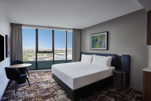 a hotel room with a bed and a large window at Adina Apartment Hotel Melbourne, Pentridge in Melbourne