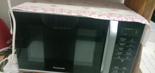 a microwave with a shelf on top of it at AZhomestay in Jitra