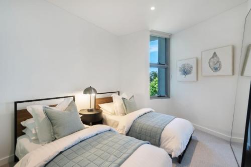 2 camas en un dormitorio con paredes blancas en Escape to Serenity by Experience Jervis Bay, en Huskisson