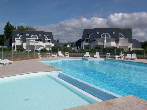 une grande piscine avec des chaises et un bâtiment dans l'établissement Carnac : Duplex 3 pièces avec Piscine Chauffée, Wifi et Parking, à 1 km de la Plage - FR-1-477-149, à Carnac