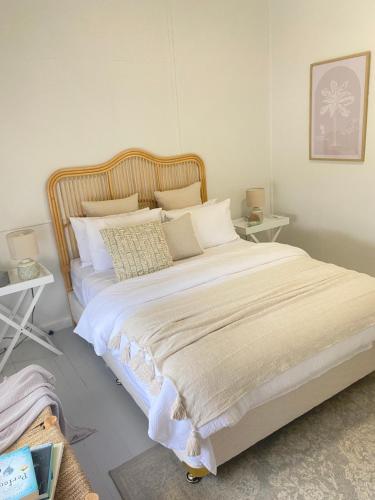 um quarto com uma cama grande com lençóis brancos e almofadas em Stay Salty em Culburra Beach