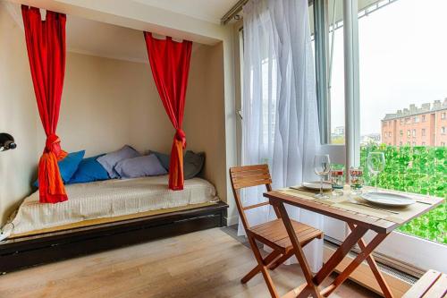 - une chambre avec un lit avec des rideaux rouges et une table dans l'établissement Studio with Balcony, à Paris