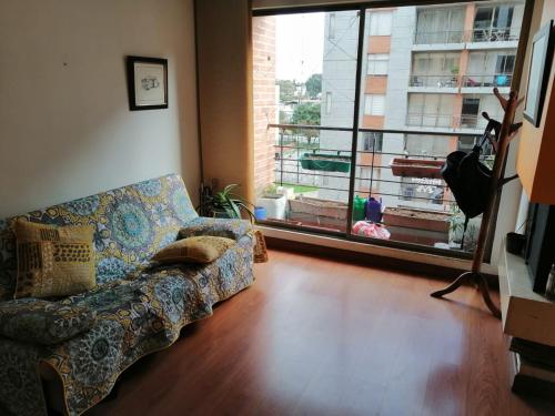 ein Wohnzimmer mit einem Sofa und einem großen Fenster in der Unterkunft Paraíso del salitre in Bogotá