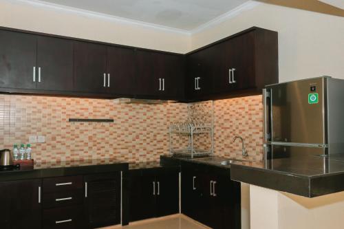 a kitchen with black cabinets and a stainless steel refrigerator at Argya Santi Resort in Jimbaran