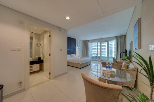 een woonkamer met een glazen tafel en een slaapkamer bij Luxurious studio Hotel Amenities in Dubai
