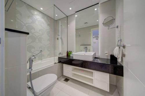 een badkamer met een wastafel, een toilet en een spiegel bij Luxurious studio Hotel Amenities in Dubai