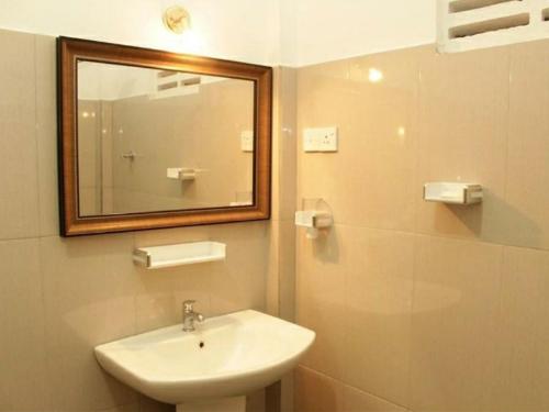 a bathroom with a sink and a mirror at Homely Guest in Habarana