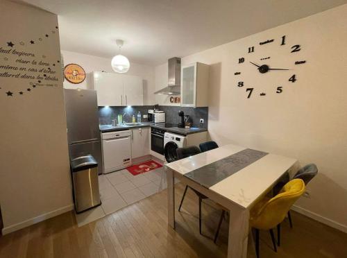 kuchnia ze stołem i zegarem na ścianie w obiekcie Luxurious Apartment Private Parking 25 MN to Paris w mieście Yerres