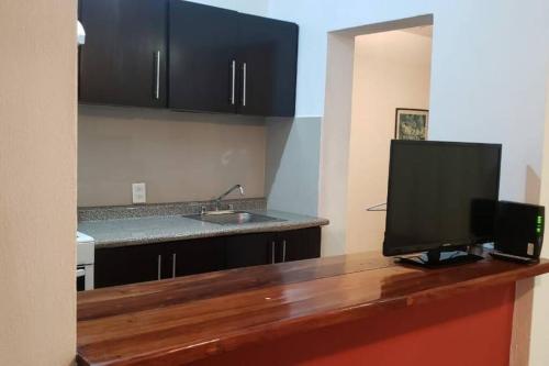 eine Küche mit einer Theke und einem TV darauf in der Unterkunft Magnifico Departamento, cocina equipada, 2 Recamaras 2 Baños , hasta 6 Personas, 3 albercas, playa a 50 mts wifi, aire acondicionado in Manzanillo