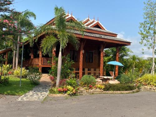 uma casa com uma palmeira em frente em Heanmaeloung Resort. em Chiang Mai