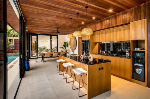 een keuken met houten kasten en een bar met krukken bij Villa Livia by BaliSuperHost in Ubud