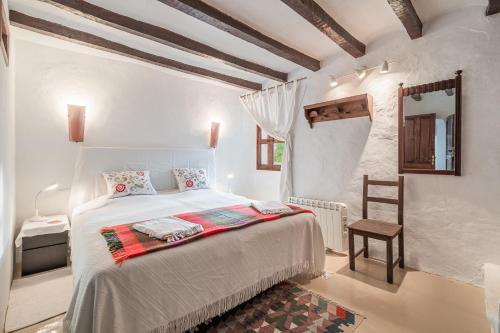 a white bedroom with a bed and a wooden ceiling at Se Teulere in Fornalutx