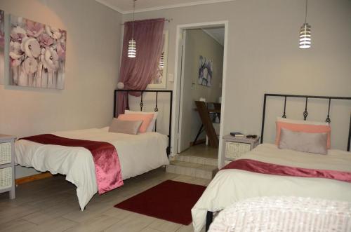 two beds in a room with pink and white at Big Tree Midrand in Midrand