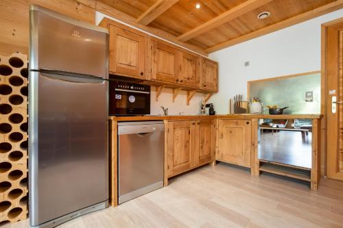 une cuisine avec des armoires en bois et un réfrigérateur en acier inoxydable dans l'établissement Appartement La Sauvageonne - Happy Rentals, à Servoz