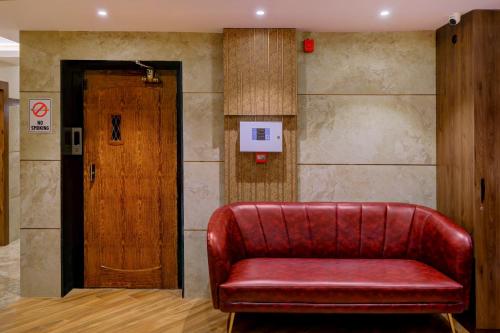 een rode leren bank in een kamer met een deur bij Metropolis Business Hotel in Panaji