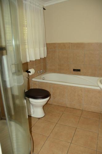 a bathroom with a toilet and a bath tub with a toilet at Big Tree Midrand in Midrand