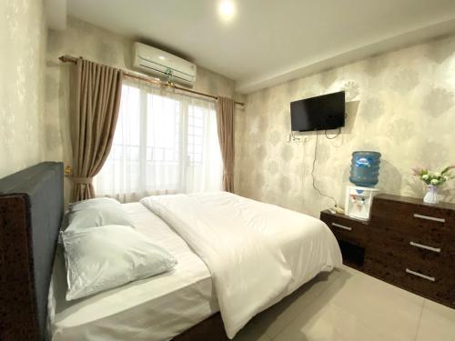 1 dormitorio con 1 cama blanca y TV en Deluxe Suites Skyview with Infinity Pool, en Sunggal