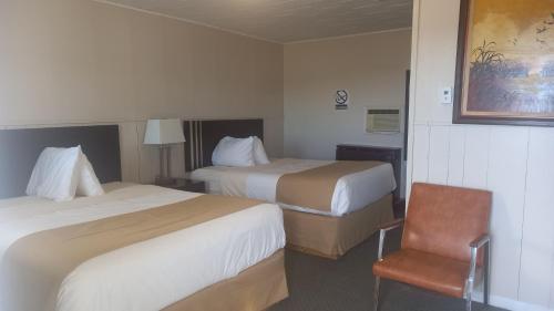 une chambre d'hôtel avec deux lits et une chaise dans l'établissement Sundown Motel, à Watrous