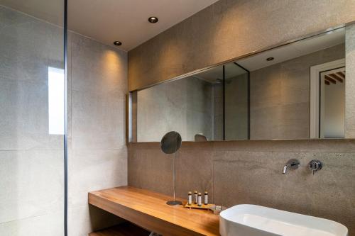a bathroom with a sink and a mirror at Uma Ray Suites in Fira