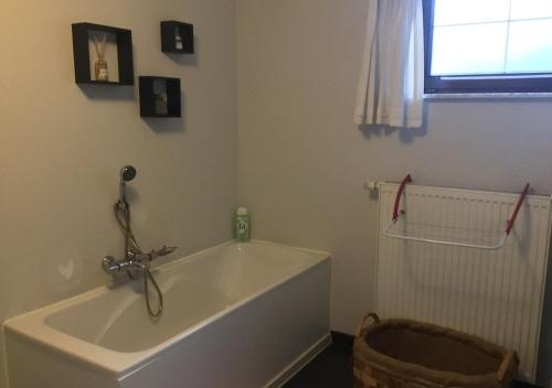 een badkamer met een wit bad en een raam bij Vakantiewoning - ‘t Ouwershuys in Opoeteren