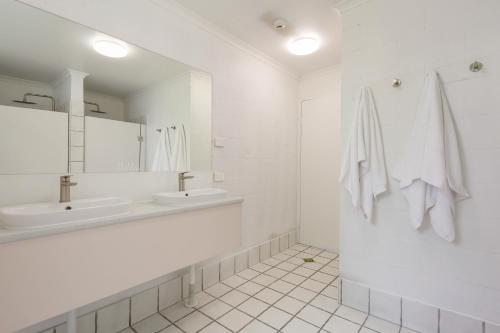 a white bathroom with a sink and a mirror at Abode Mooloolaba, Backpackers & Motel rooms in Mooloolaba