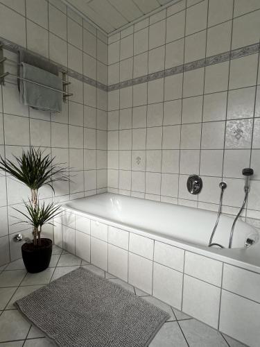 a white bathroom with a tub and a plant at Ferienwohnung Moselzeit in Alken