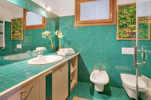 a blue tiled bathroom with a toilet and a sink at Casa Rossella in Bormio