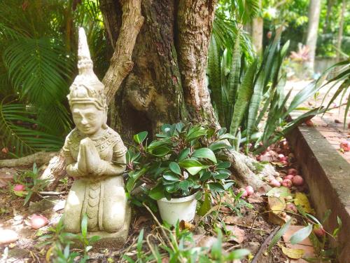 a statue sitting next to a tree in a garden at Casa Kep Eco Bed & Breakfast in Kep