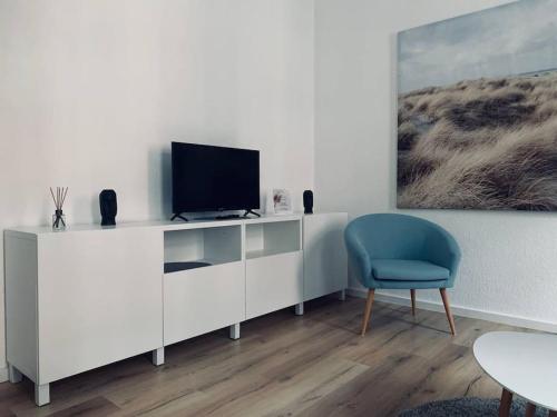 un soggiorno con TV e sedia blu di work & travel apartment a Meißen