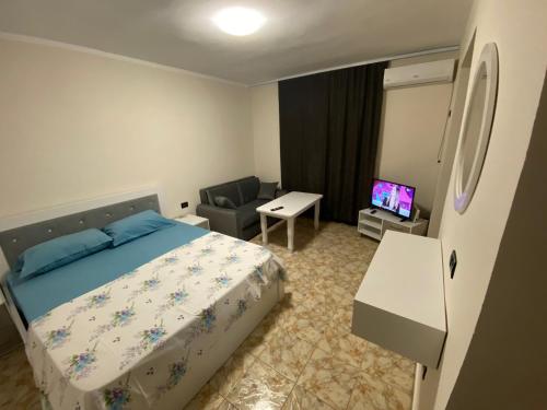 a bedroom with a bed and a chair and a television at Cappuccino City Center Apartment in Lezhë