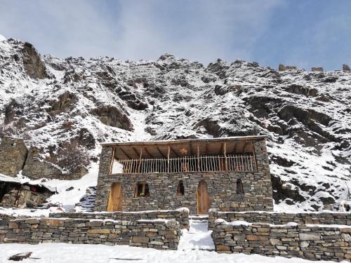 a stone building in front of a snow covered mountain at Fortress House Khakhabo in Khakhabo