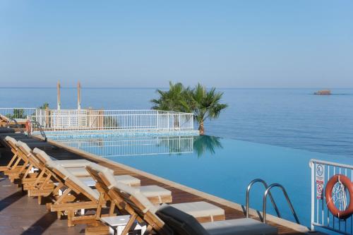 a pool with chairs and the ocean in the background at Little Bird Lesvos in Petra