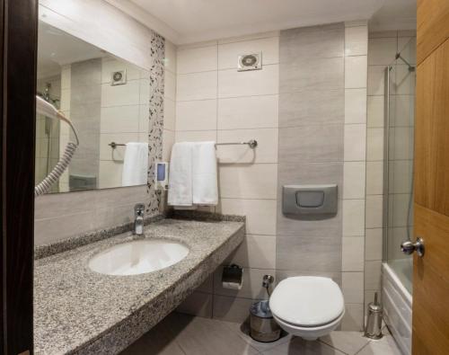 a bathroom with a sink and a toilet and a mirror at Kandelor Hotel in Alanya