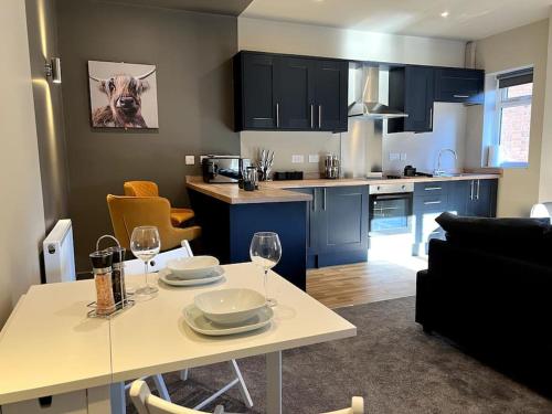 a kitchen and living room with a table with wine glasses at Modern 1BR Apartment near Loughborough University & Hospital in Loughborough