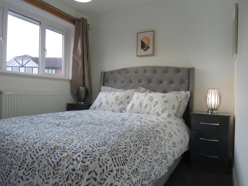 a bed with a blue and white comforter and a window at Remarkable and perfect 3 Bed House in Nottingham in Nottingham