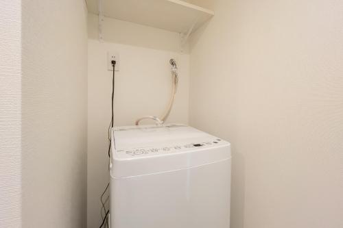 a small white refrigerator in a corner of a room at MAT OSHIAGE Ⅱ in Tokyo