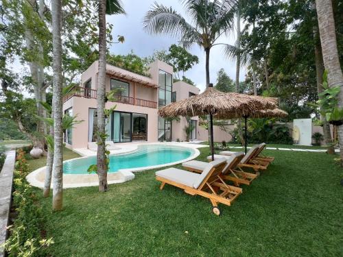 een huis met een zwembad met stoelen en een parasol bij Sealuna Villas in Tanah Lot