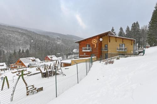 a snow covered cabin with a fence in front of it at Hotel Jirinka in Dolní Morava