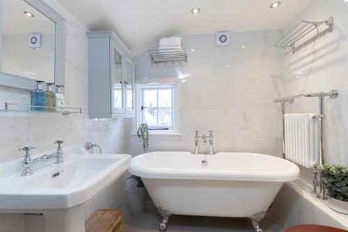 Baño blanco con 2 lavabos y bañera en Beautiful 4 Bedroom Home en Cheltenham