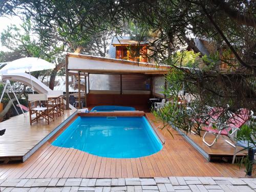 a swimming pool on a wooden deck with a house at Cabanas Las Escondidas in Monte Hermoso