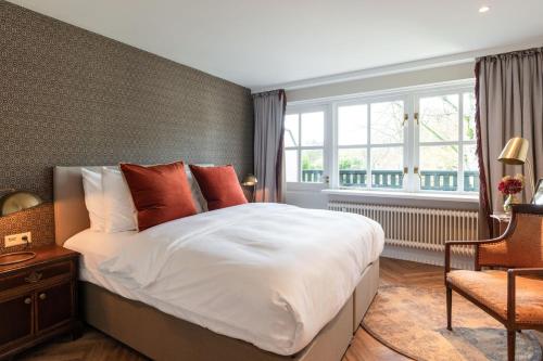 a bedroom with a large white bed and a window at Boetiekhotel De Kastanjehof in Lage-Vuursche