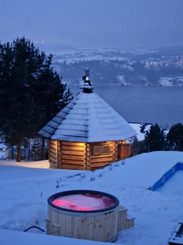 domek z bali na śniegu z wanną z przodu w obiekcie Mergen Bike & Ski Resort w mieście Niedzica Zamek