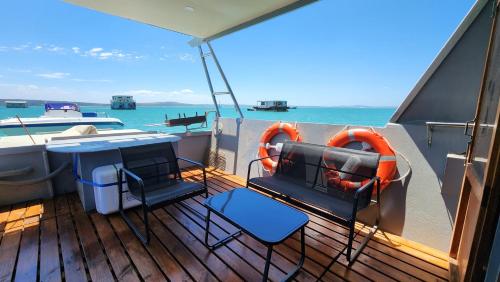 a deck with a table and chairs on a boat at Kraalbaai Lifestyle House Boats in Langebaan