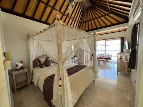 - une chambre avec un grand lit à baldaquin dans l'établissement Puri Wirata Dive Resort and Spa Amed, à Amed