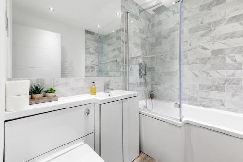 a white bathroom with a tub and a sink and a shower at Reading Town Centre 1 & 2 Bedroom Apartments with Parking by 360Stays in Reading