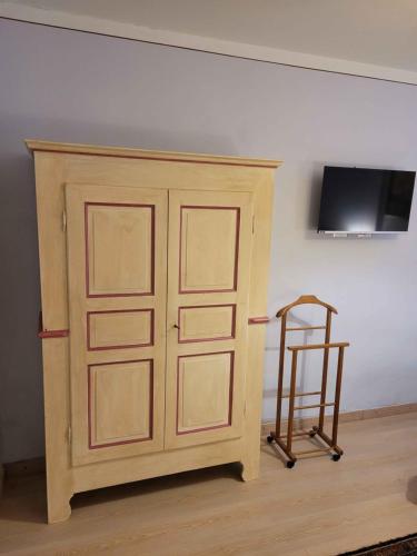 a wooden cabinet with a chair next to a wall at B&B Villa Tavallini in Pollone